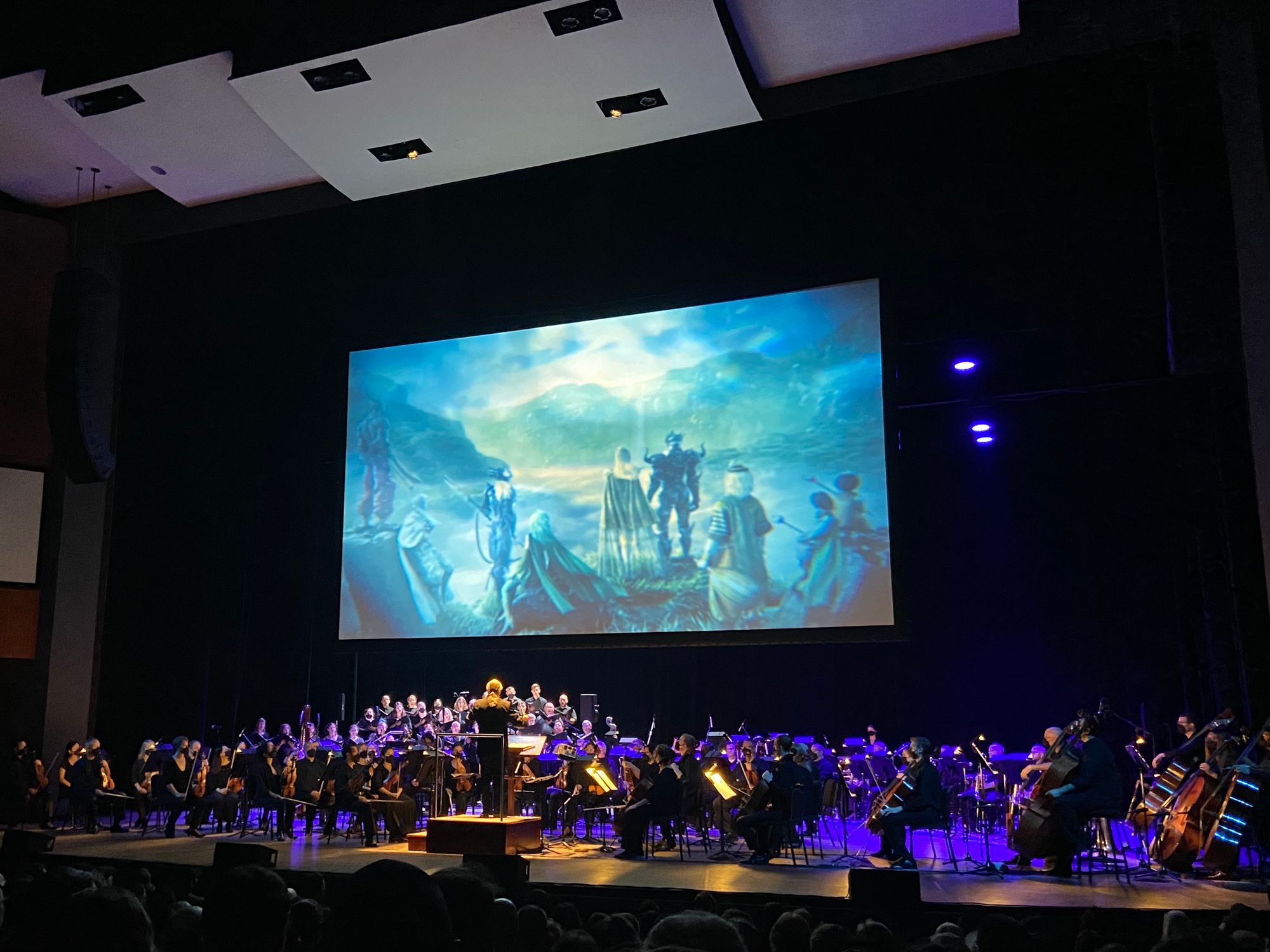 Symphony under purple lights in front of a screen showing a scene from Final Fantasy