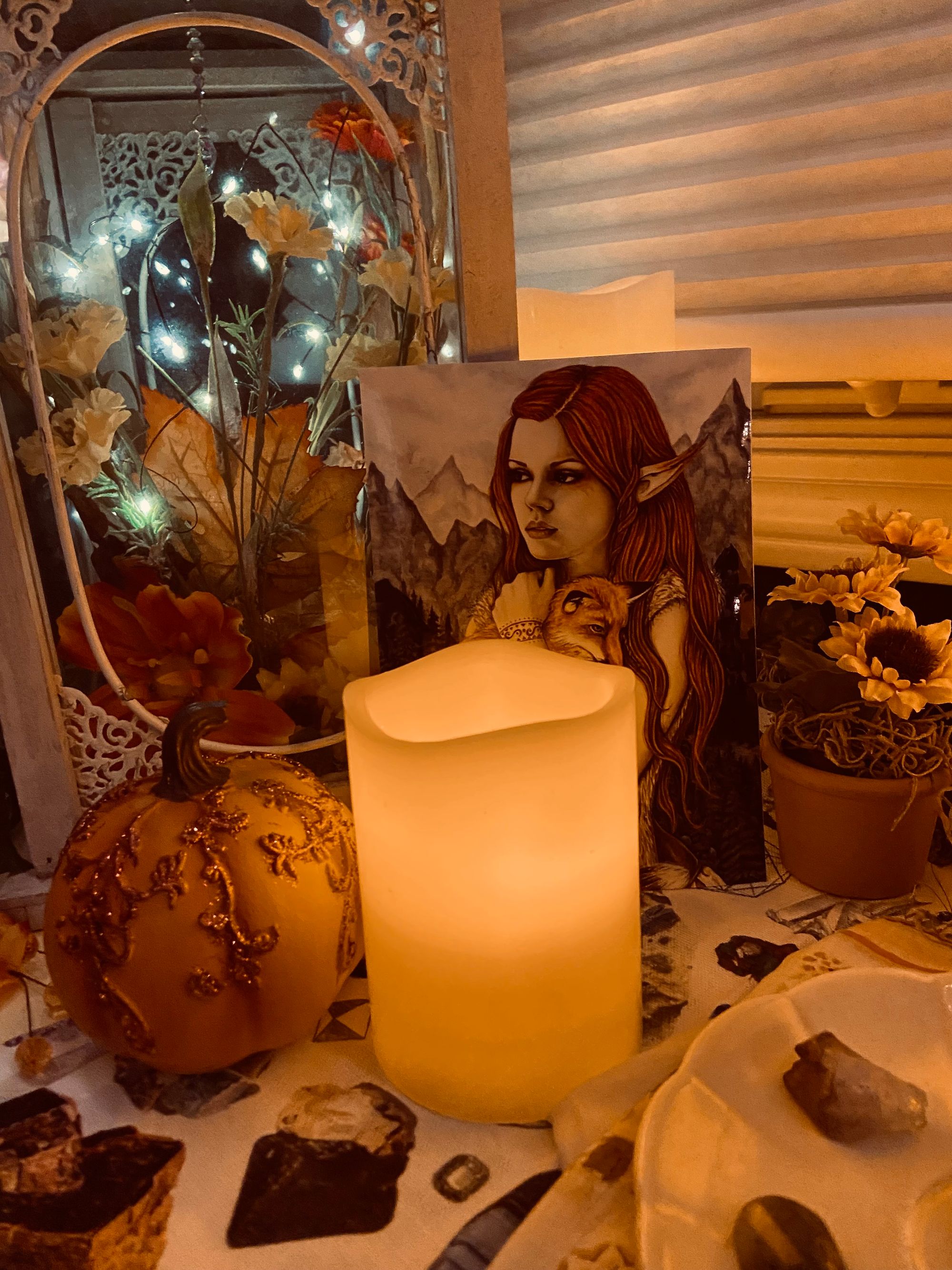  Candles next to a sparkly pumpkin, sunflowers, and a painting of a fairy and fox