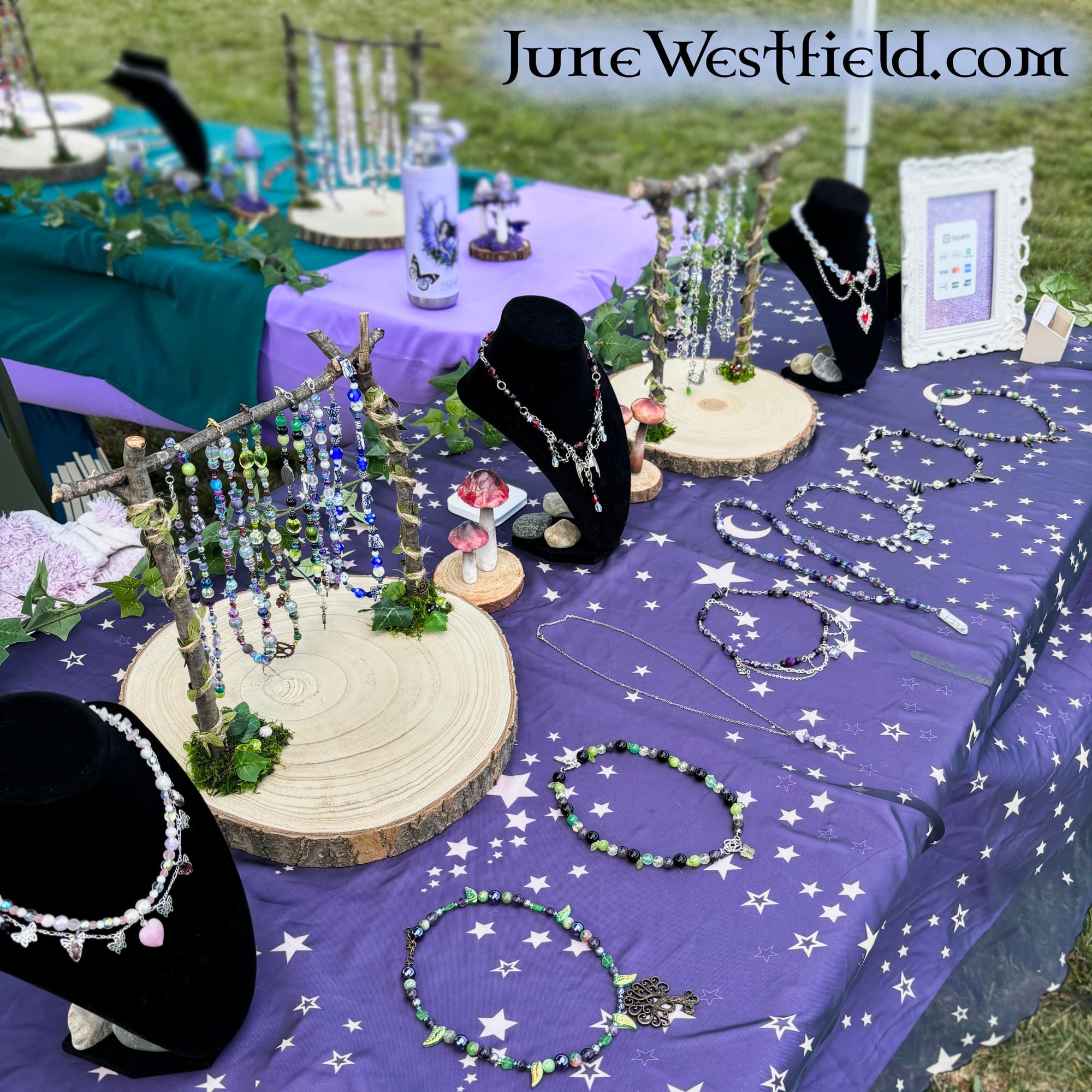 Lots of beaded necklaces laid across purple tables outdoors